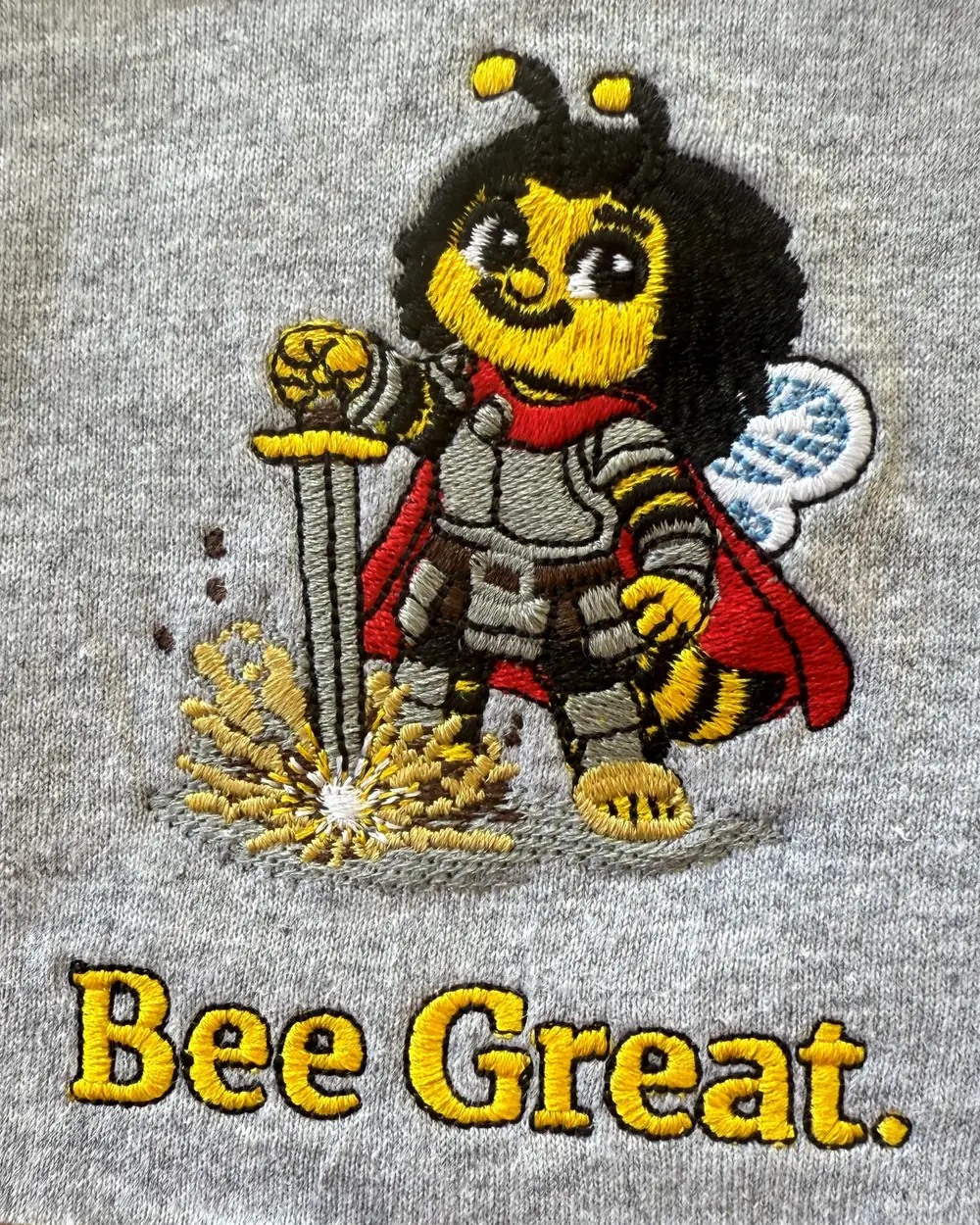 The Bee Great Nectar design stitched in thread on sample fabric.